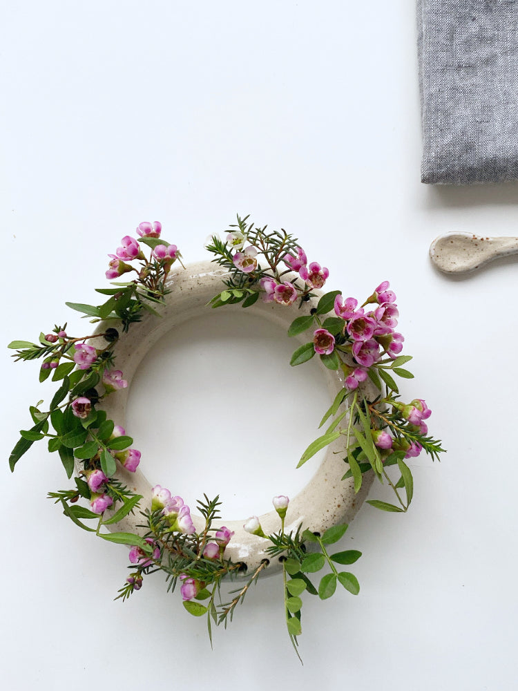 Handgemaakte ronde bloemenvaas met verschillende kleine zelfgeplukte bloemen erin