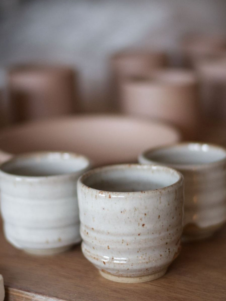 Drie handgemaakte keramieken kopjes met wit glazuur en subtiele spikkels
