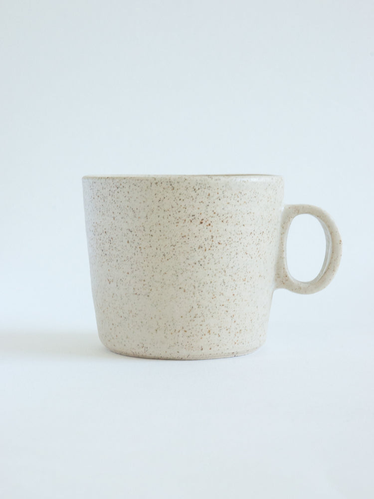 Handgemaakte lichtgespikkelde keramieken mok op witte achtergrond