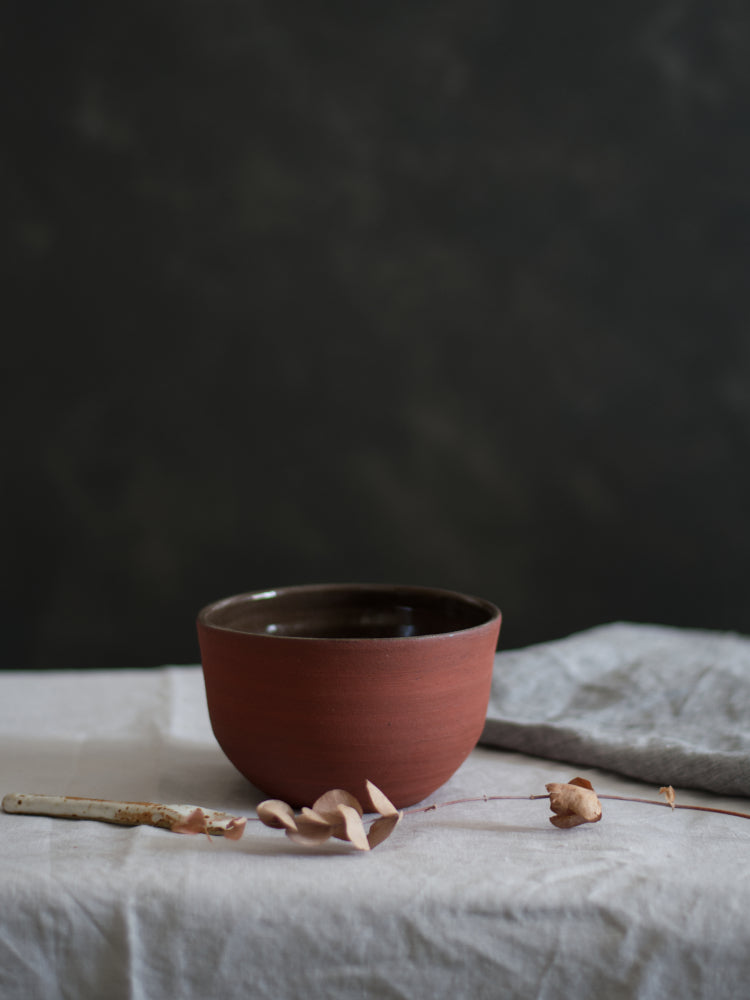 Rode kom op grijs tafelkleed met keramieken lepel en theedoek