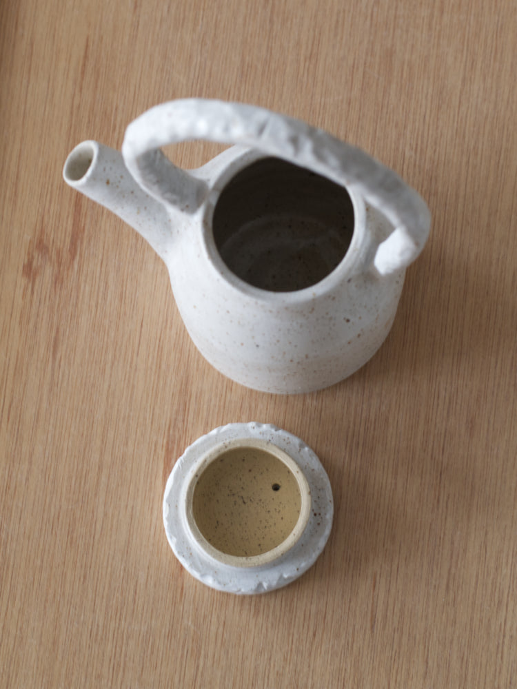Handgemaakte theepot met whitewashed en deksel ernaast van boven gefotografeerd