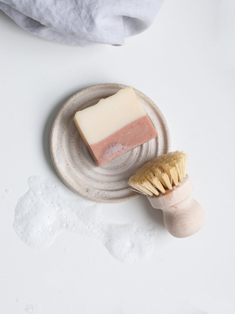 Handgemaakt keramieken zeepbakje met roze en witte zeep in spiraalvorm, op lichte achtergrond