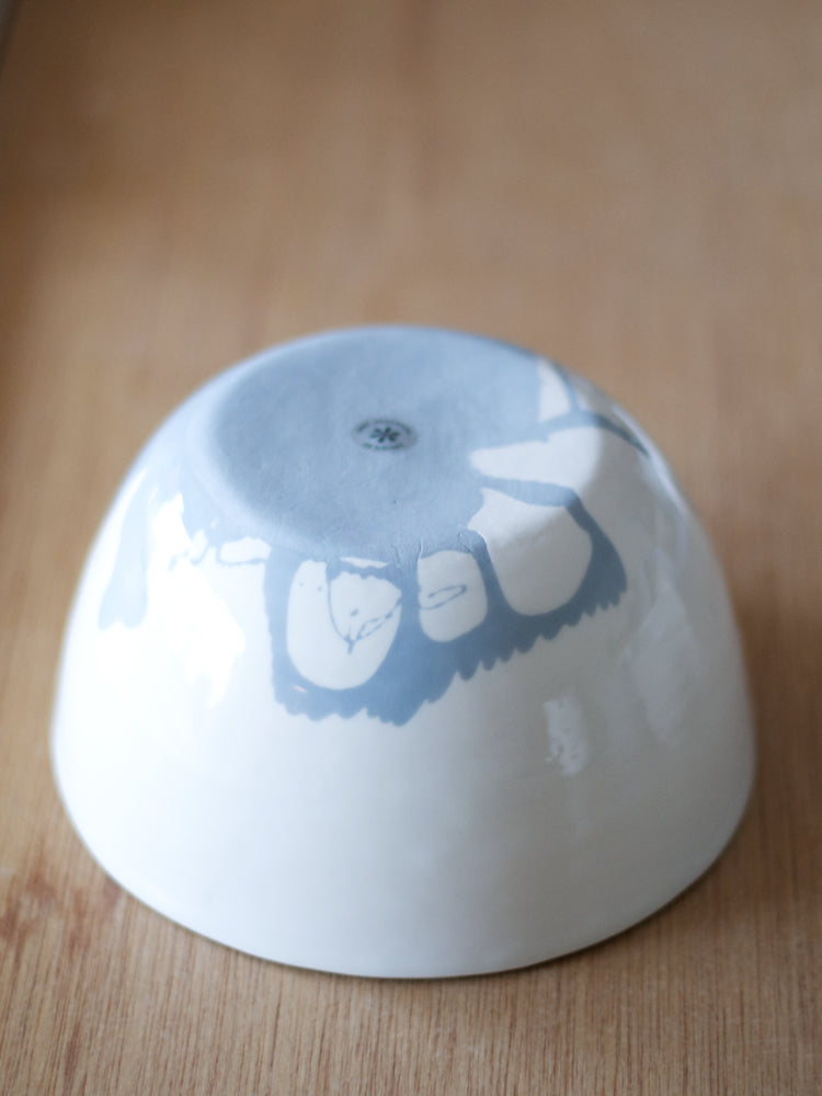 Handgemaakte schaal van wit porselein met een bodem van blauw porselein, grillig patroon. De onderzijde gefotografeerd