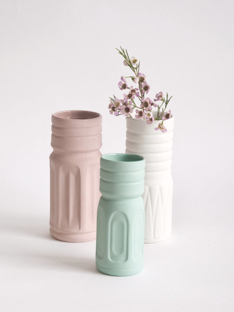 Gekleurde porseleinen vaasjes tegen een witte achtergrond