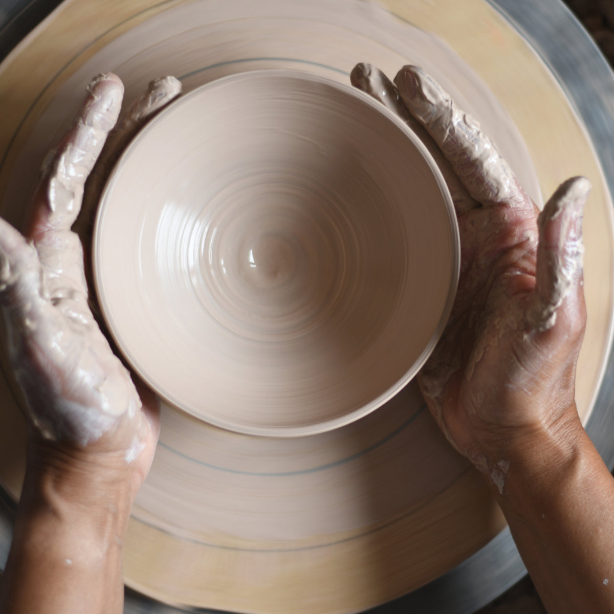 Vrouwenhanden met kleislib, al draaiend achter de draaischijf