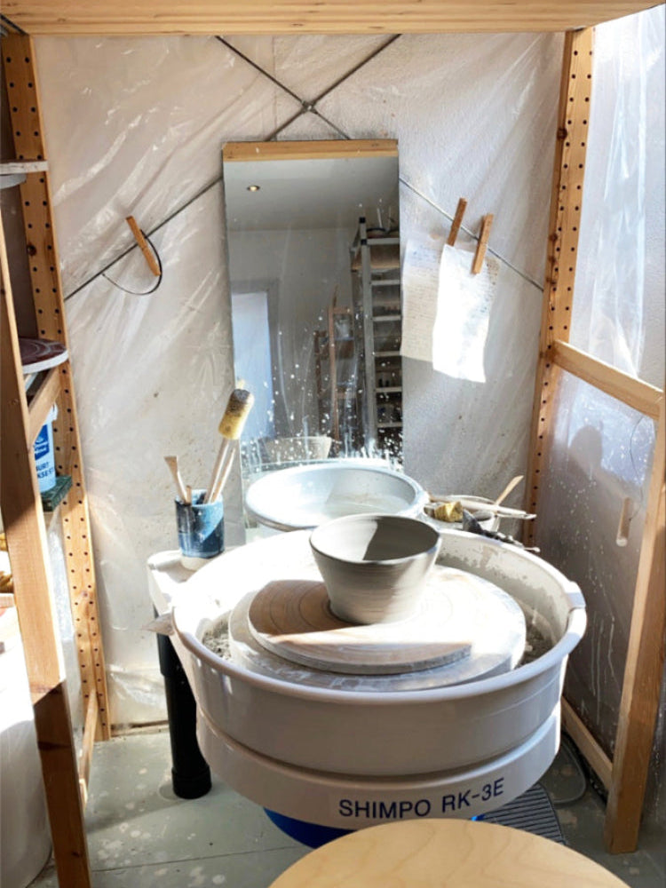 Handgedraaide kom op een pottenbakkersdraaischijf in het atelier waar de zon op valt