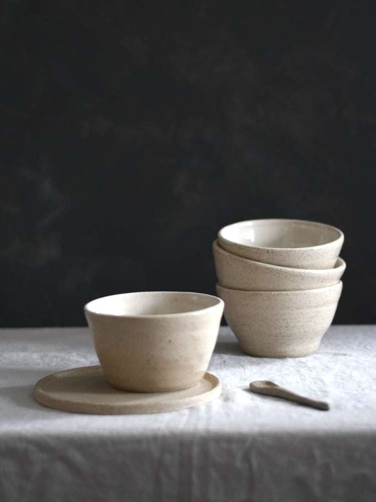 Handgemaakte keramiek kommen gestapeld op een tafelkleed met een donkere achtergrond