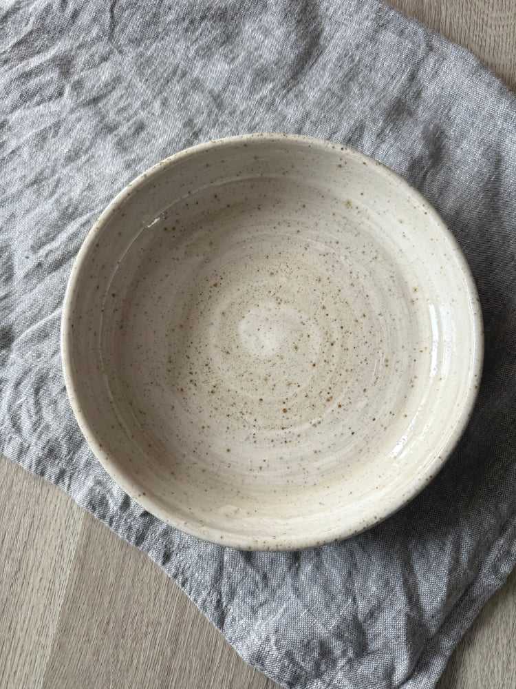 handgemaakte keramieken kom op grijsblauwe theedoek