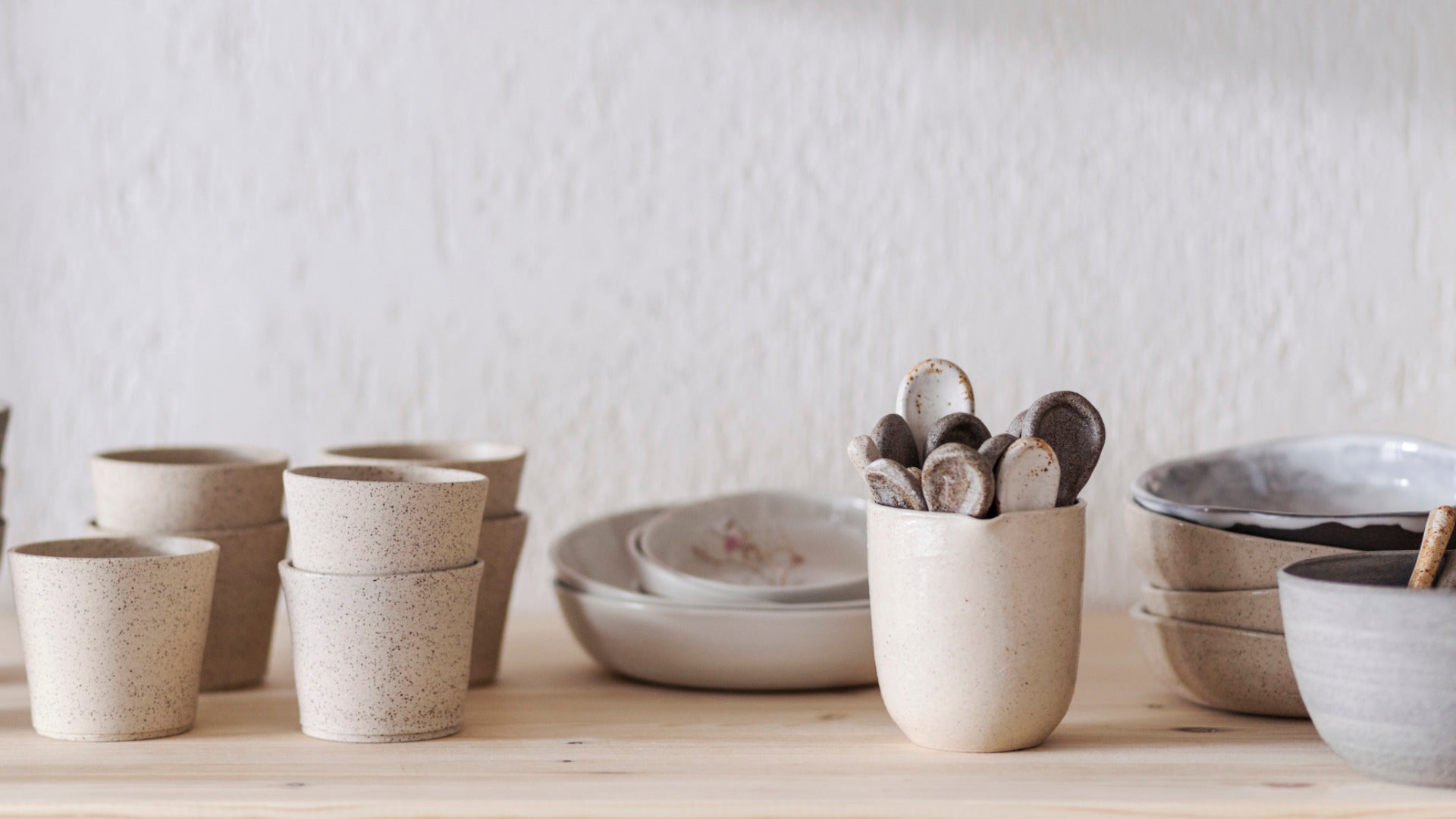 Verschillend handgemaakt servies op een plank in een atelier, allemaal naast elkaar opgesteld