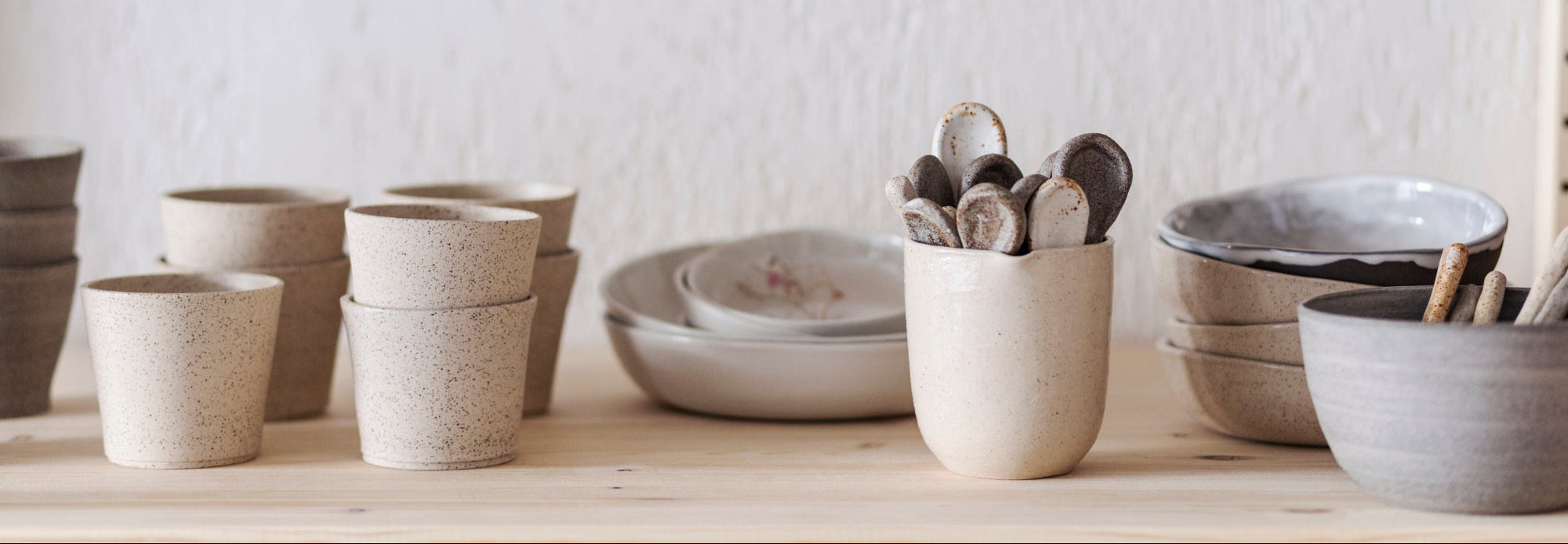 Handgemaakt servies, verschillende items, op een rijtje in een atelier op een houten plank