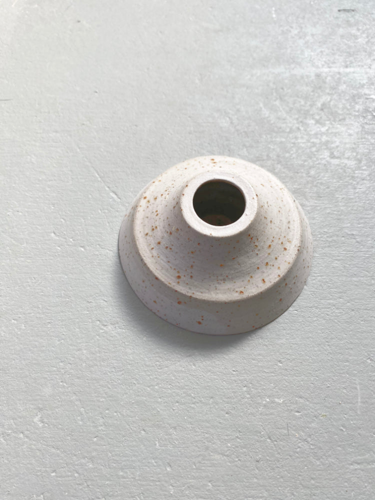 Handgemaakte whitewashed kandelaar van keramiek op een grijze achtergrond.