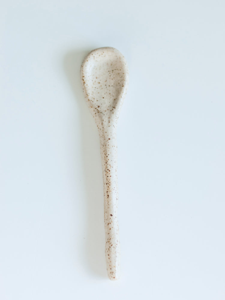 Handgemaakte lichtgespikkelde lepel op een witte achtergrond