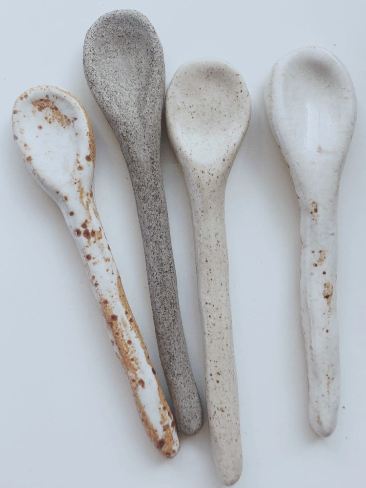 Verschillende handgemaakte keramieken lepels op een rijtje op witte achtergrond