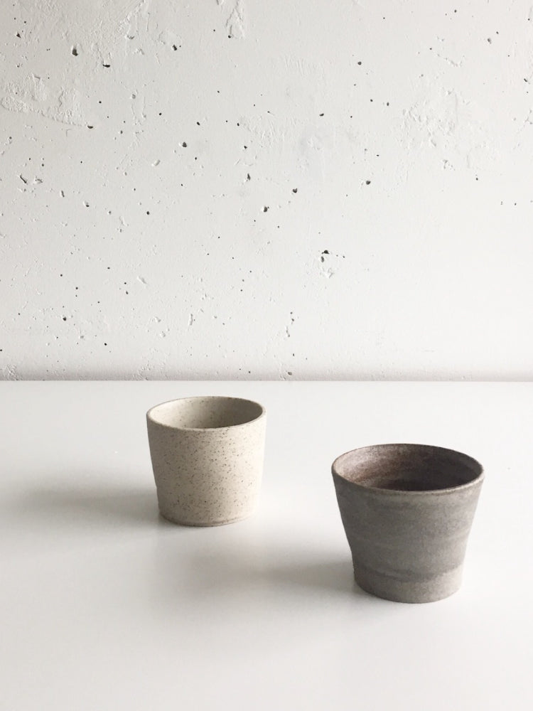Handgemaakt licht en donker keramieken kopje voor een witte muur