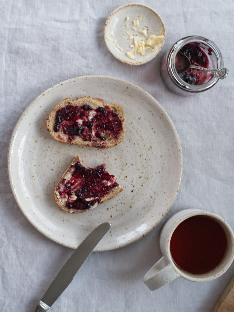Bord van handgemaakt gespikkeld steengoed met glanzend glazuur, gevuld met boterhammen