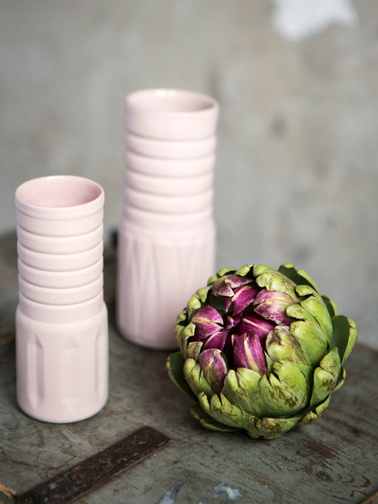 Gekleurde porseleinen vaasjes op houten ondergrond met artisjok ernaast. Fotocredits: Kyonne Leyser