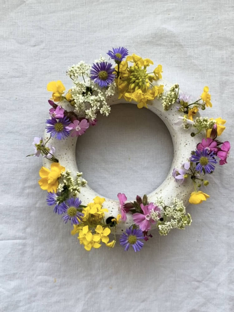Ronde handgemaakte bloemenvaas van keramiek met zelfgeplukte kleurrijke bloemen.