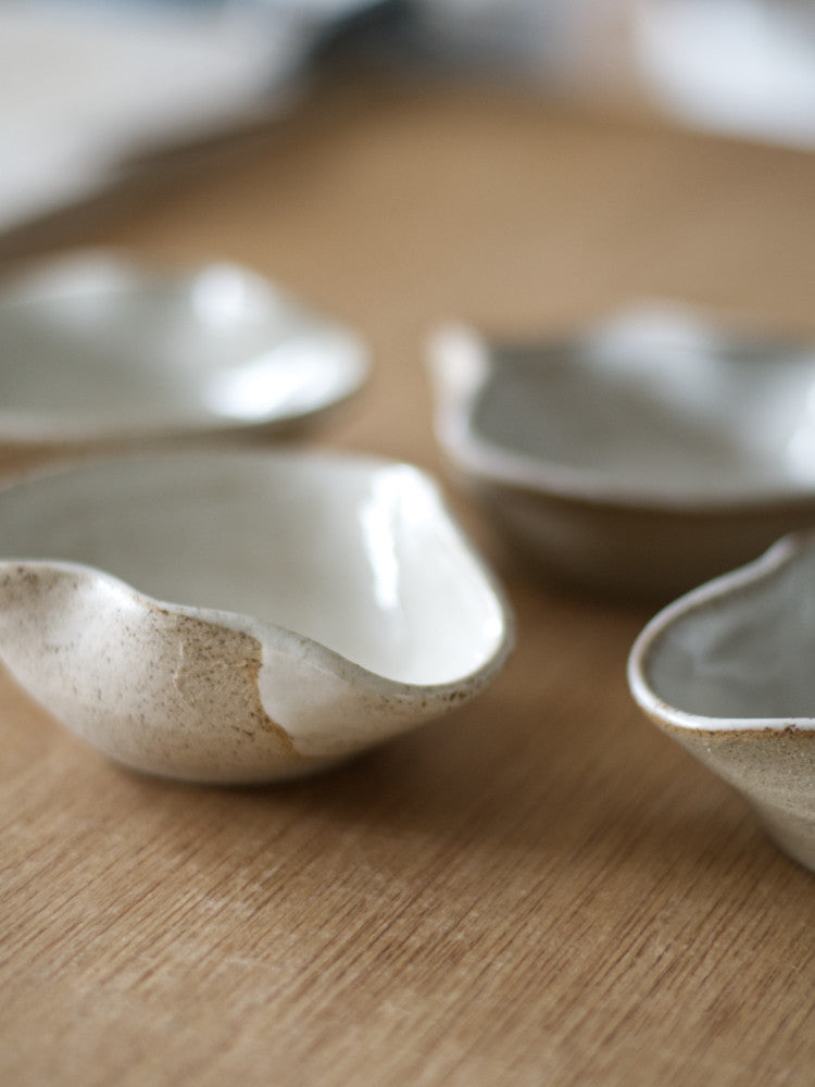 handgemaakte schaaltjes van keramiek, golvend patroon met wit glazuur binnenin, closeup, op houten tafel
