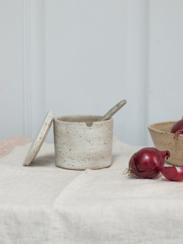 Suikerpot handgemaakt met het deksel ernaast en een handgemaakte lepel erin, closeup