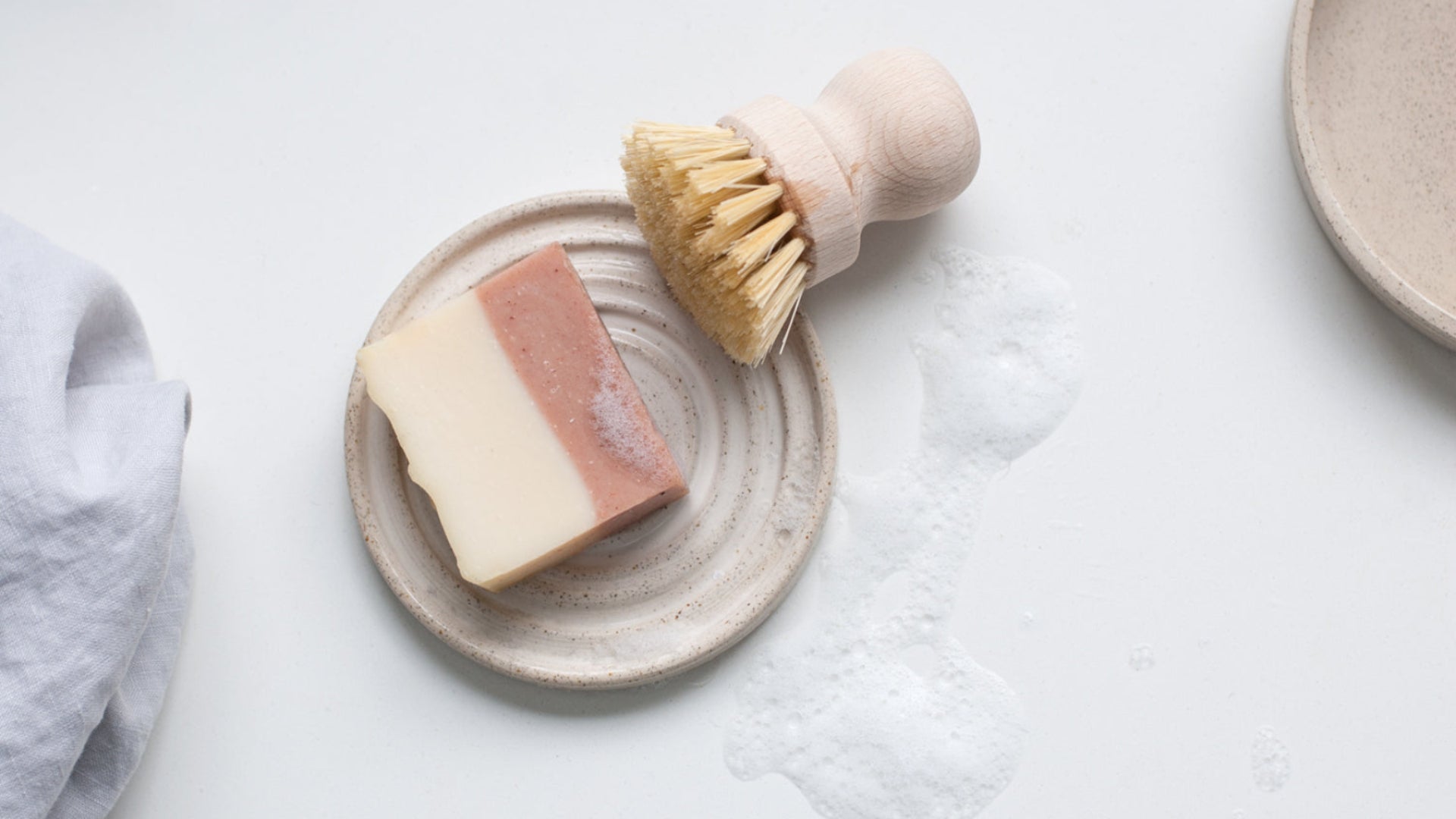 Handgemaakt keramiek zeepbakje met zeep, schuim, borstel en handdoek.