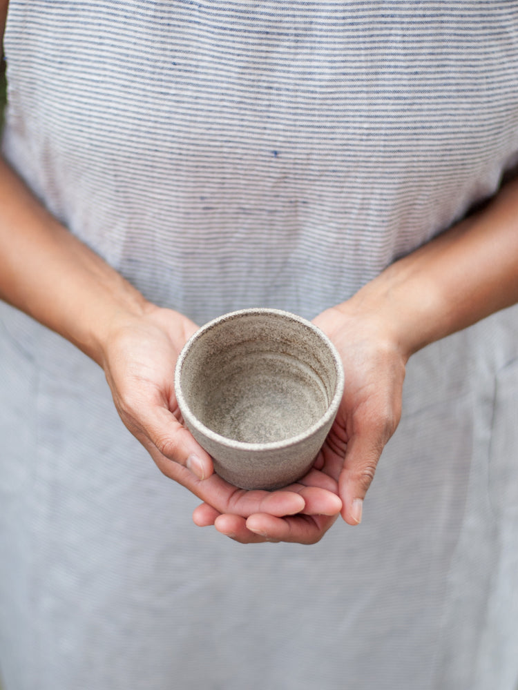 Handen die een handgemaakt keramiek kopje vasthouden