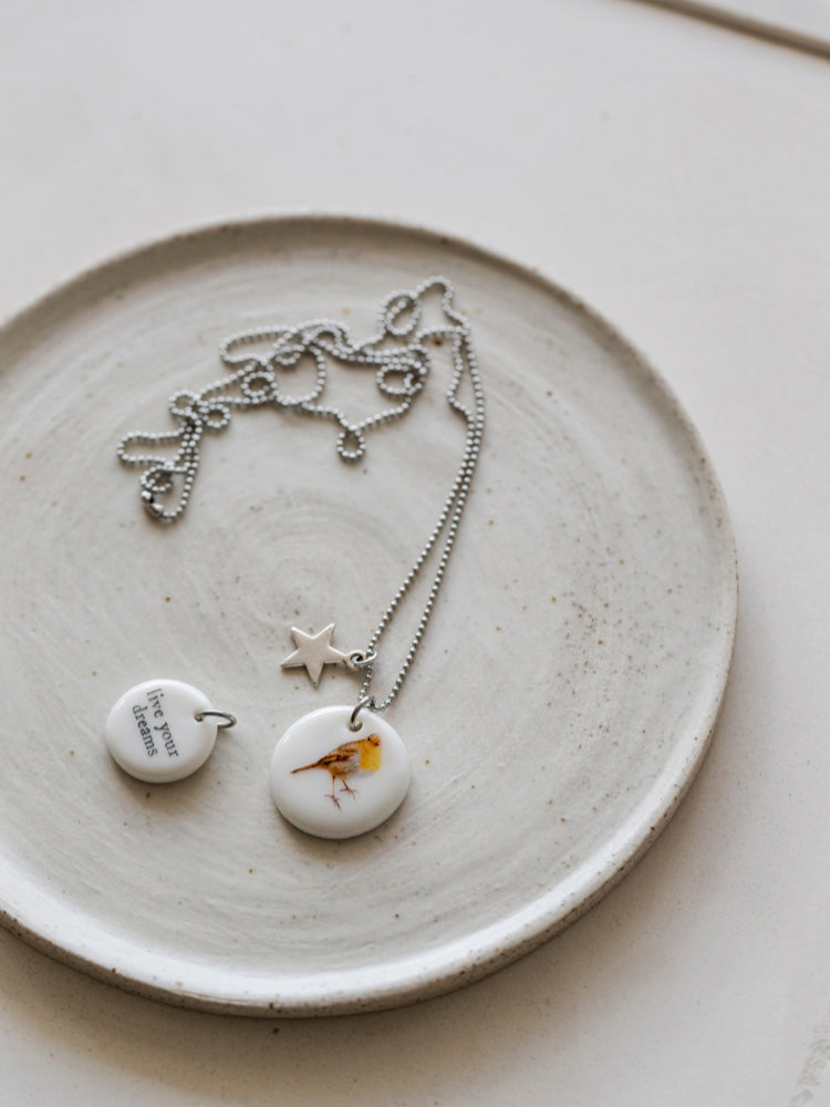 Handgemaakte keramieken ketting met een hartje en love op een roze doek