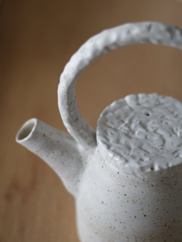Handgemaakte theepot met whitewashed met reliëf deksel en handvat closeup gefotografeerd