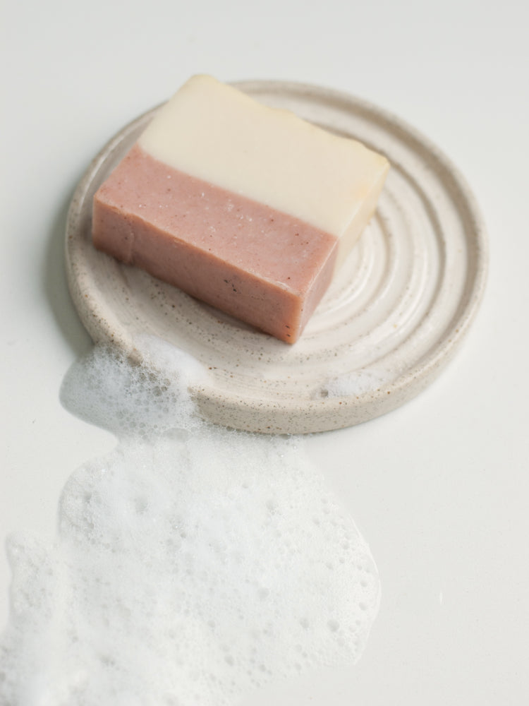 Handgemaakt keramieken zeepbakje in spiraalvorm met roze en witte zeep, op lichte achtergrond