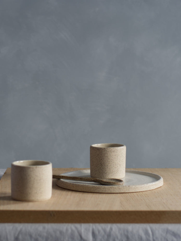 Twee handgemaakte espressokopjes en cakebord keramiek op houten plank