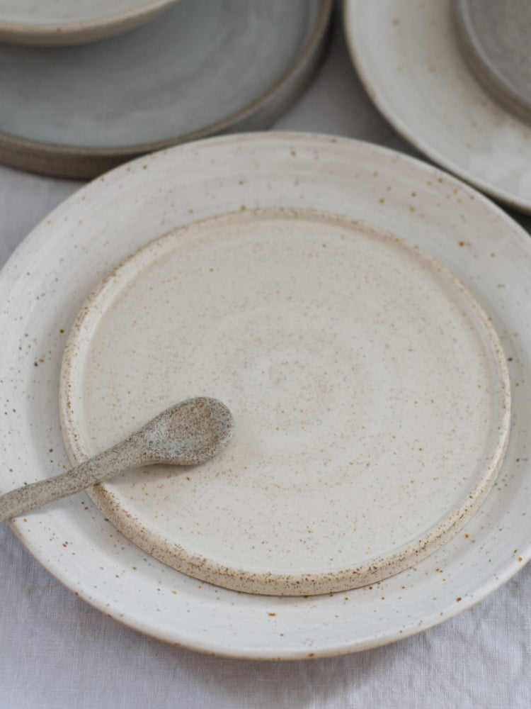 Handgemaakt cakebord op een dinerbord gestapeld met een keramieken lepel erop