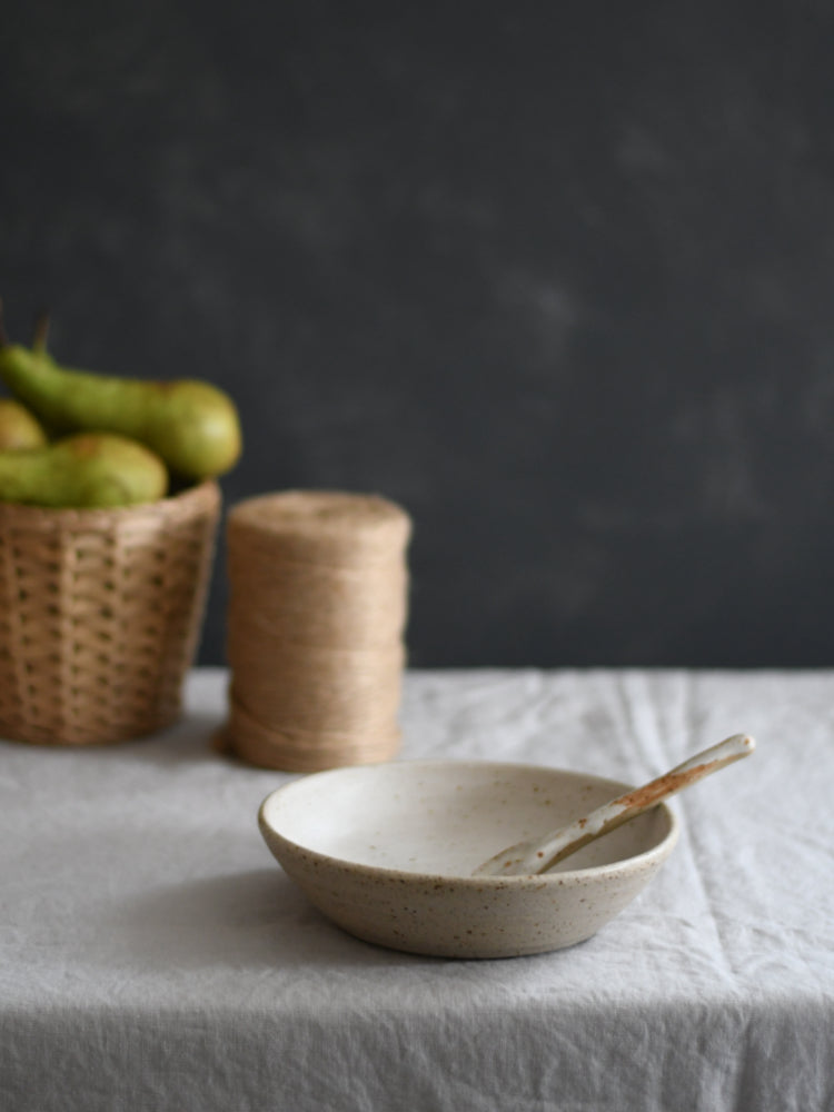 Handgemaakt keramiek kom op een tafelkleed met donkere achtergrond