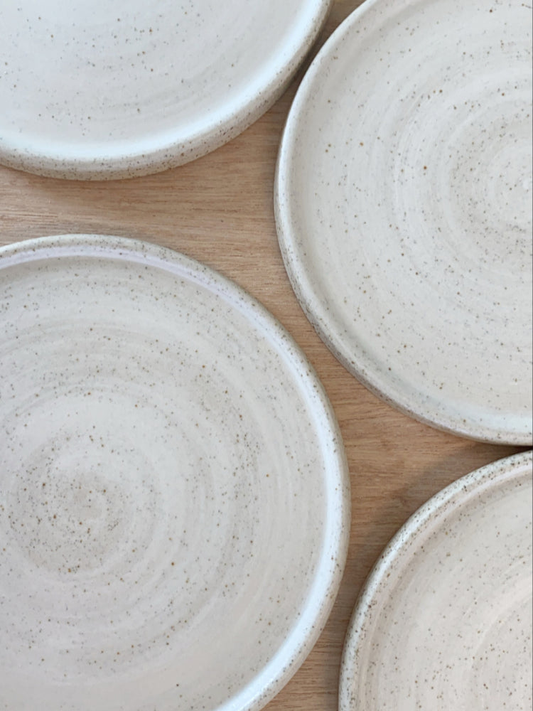 verschillende handgemaakte whitewashed keramiek cakeborden op houten achtergrond