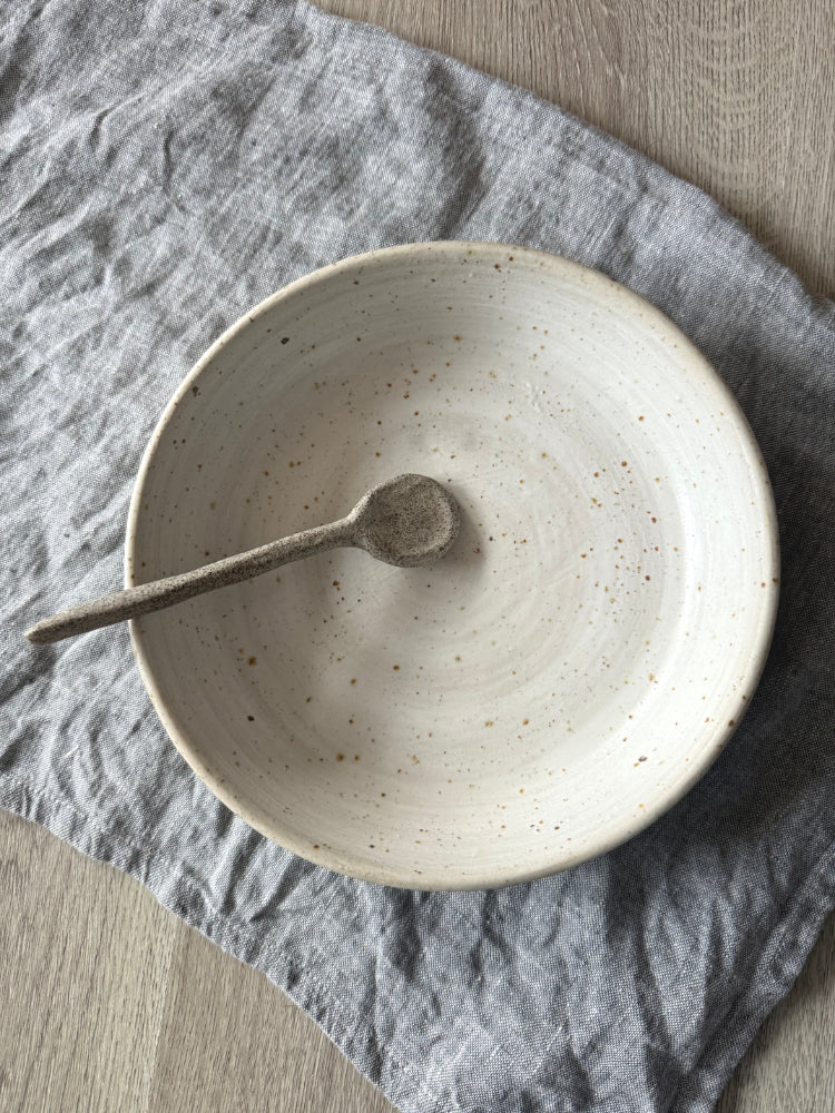 handgemaakte keramieken whitewashed kom met mat glazuur op grijze theedoek