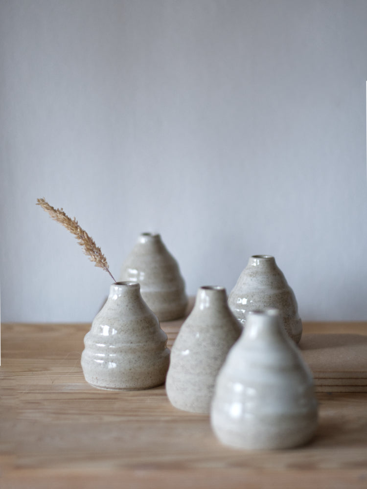 Handgemaakte kleine vaasjes op een rijtje, gemaakt van gespikkelde klei met licht golvende vorm