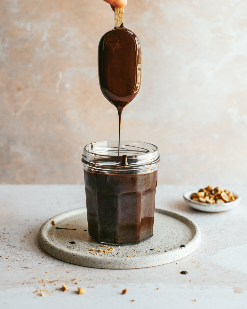 IJsje dat in chocolade wordt gedoopt, geserveerd op een handgemaakt licht gespikkeld cakebord van keramiek