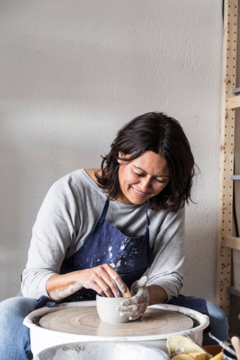 Imre Bergmann, keramiste, achter de draaischijf waarop ze een kopje draait. 