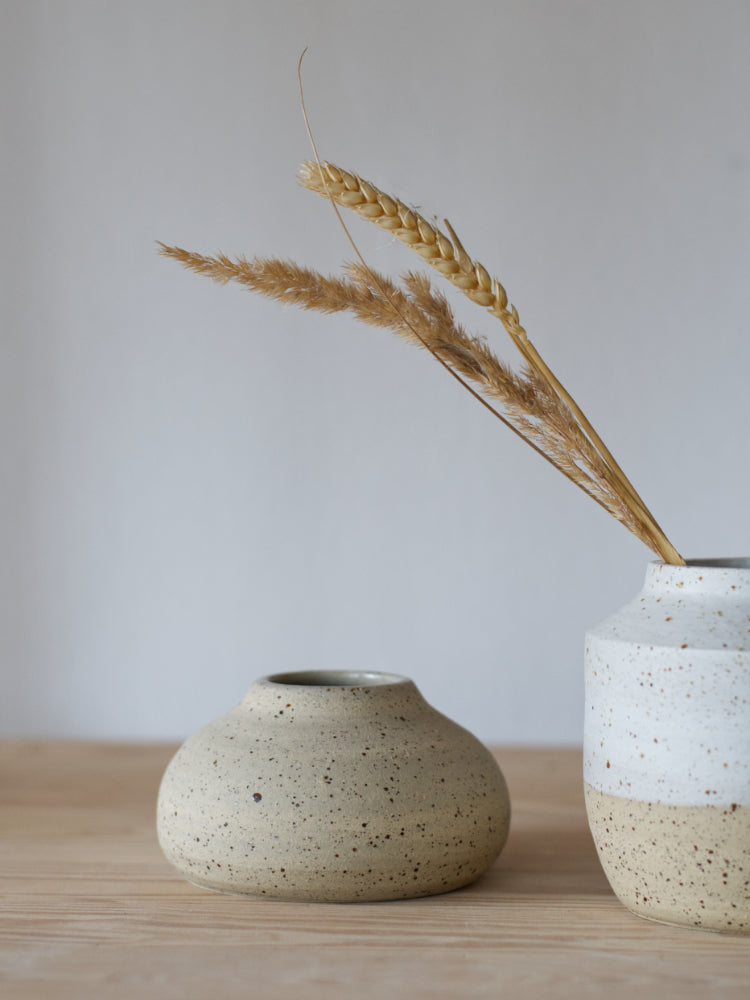 Handgemaakt vaasje gespikkelde klei ongeglazuurde buitenzijde met een vaasje met graspluimen ernaast 