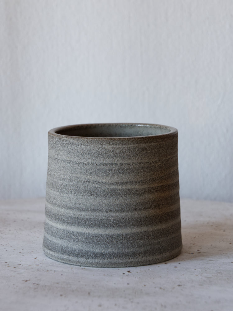 Handgemaakt kopje van donkere klei, ongeglazuurde buitenkant, close up gefotografeerd