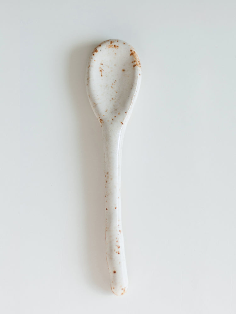 Handgemaakte lepel keramiek, wit geglazuurd met rode plekken, op een witte achtergrond 