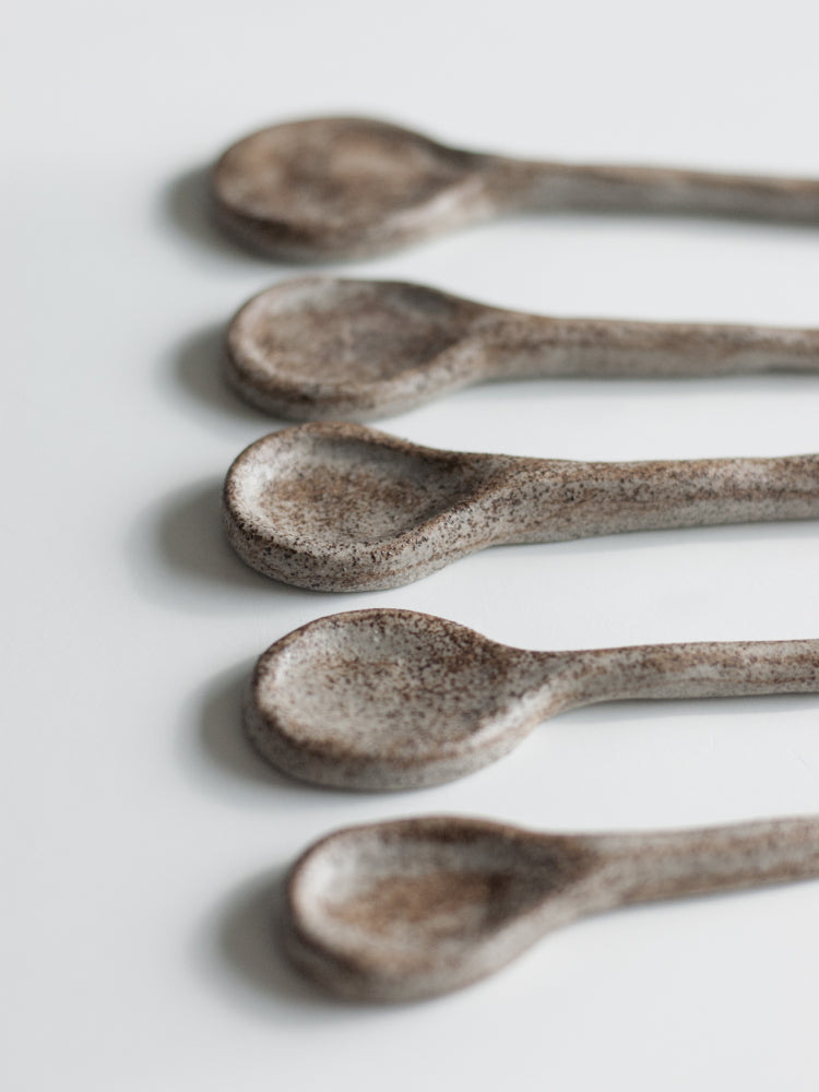 Handgemaakte lepels van grijs/bruin keramiek op een rijtje gefotografeerd, close up