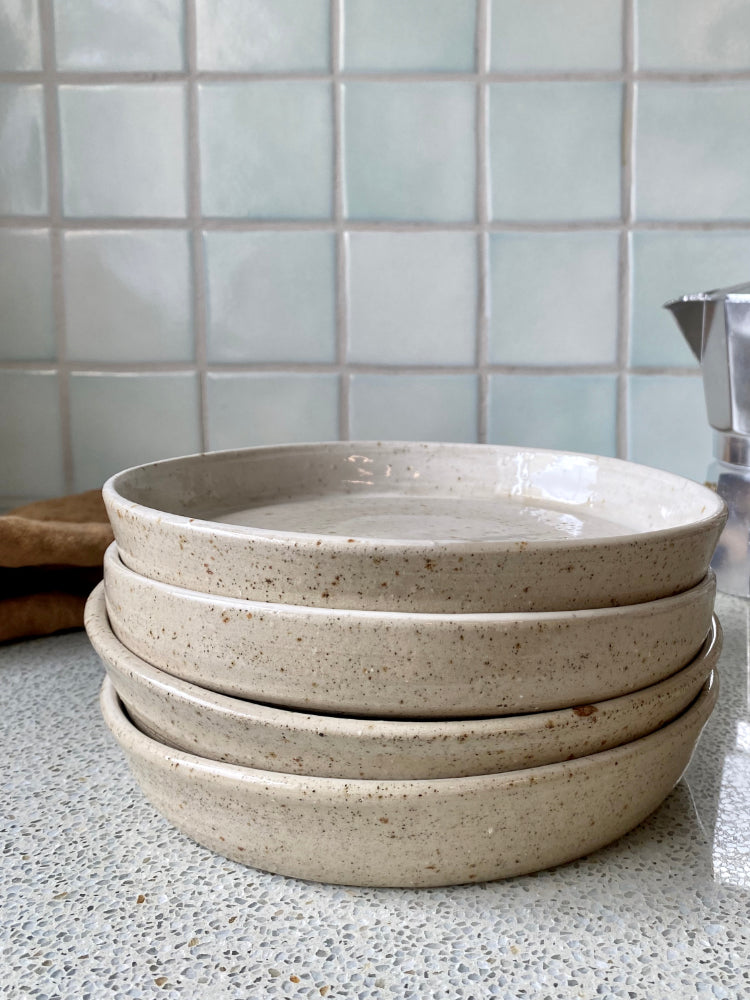 gestapelde handgemaakte lage kommen voor een lichtgroene tegelmuur