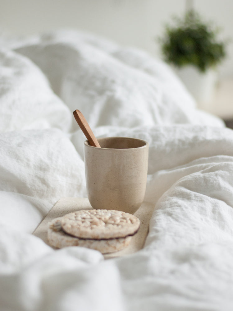Handgemaakte theekop op een dienblad in bed tussen zachte dekens 