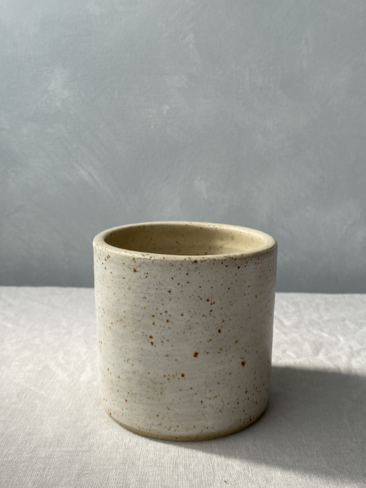 Handgemaakte toiletborstelhouder van gespikkeld keramiek, close up, op een lichtgrijze achtergrond