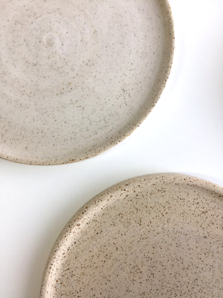 Twee handgemaakte keramieken cakeborden met whitewash en gespikkeld glazuur